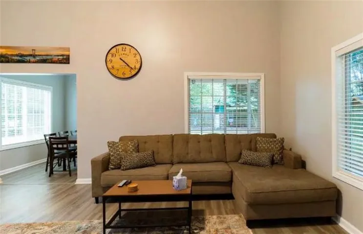 Vaulted ceilings, wood-finish flooring, and multiple windows with blinds