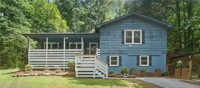 Split-level exterior featuring blue horizontal siding and a covered front porch with white railing