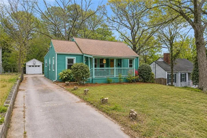 Charming cottage with  covered front porch, situated on a landscaped lot with mature trees