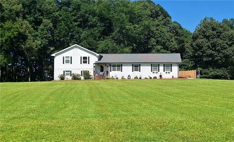 White exterior residence featuring a front porch with brick stairs, black shutters, and a gray shingle roof