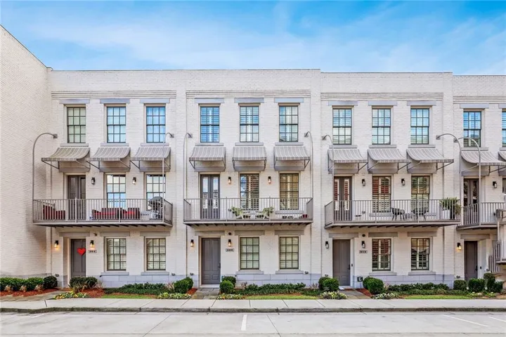 White brick exterior with multiple private balconies, each featuring metal railings and fabric awnings