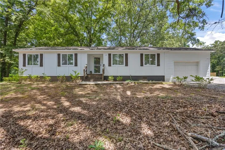 Single story home featuring an attached garage, crawl space, board and batten siding, and driveway