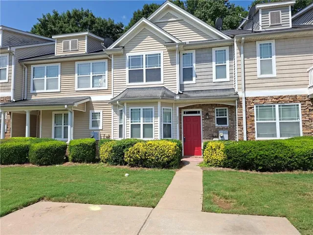Siding exterior with brick accents and a red entry door