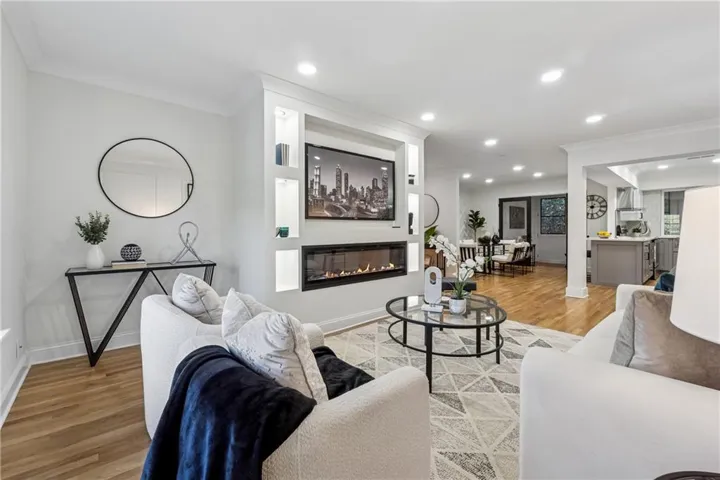 Built-in media center with shelving and integrated linear fireplace, recessed lighting, crown molding, and wood-finish flooring