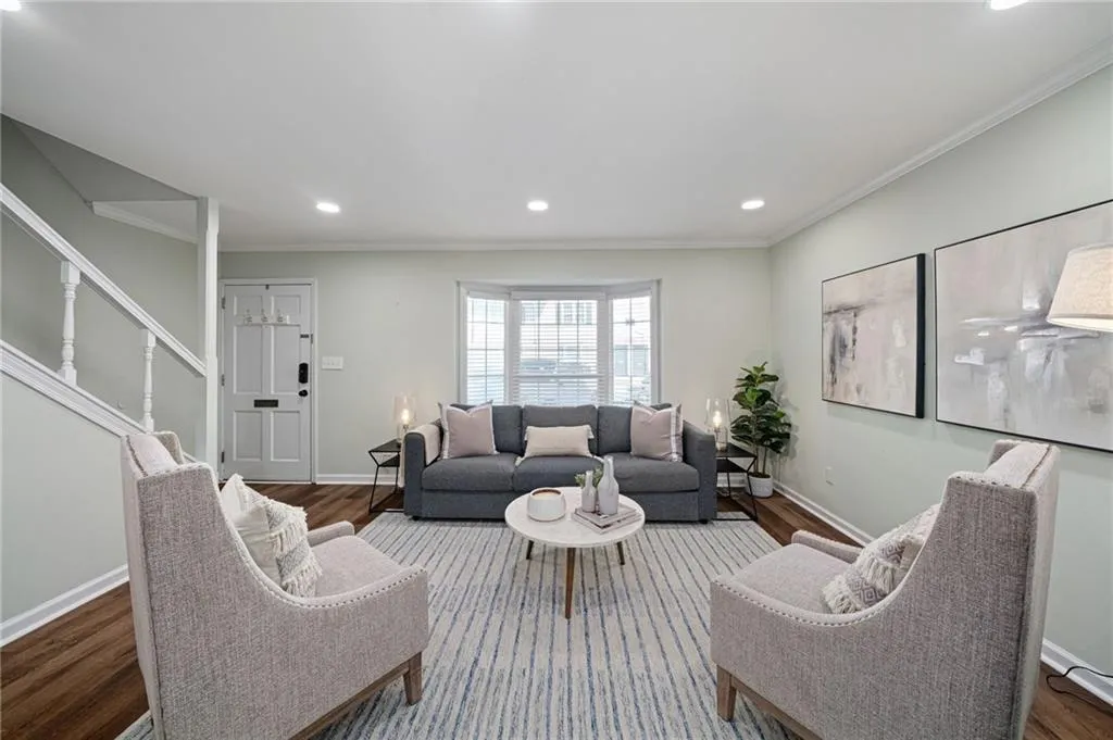 Living area with wood-finish flooring, recessed lighting, and a bay window featuring white blinds