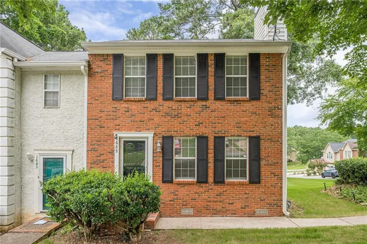 Charming brick colonial featuring black shutters and multi-pane windows across the front facade