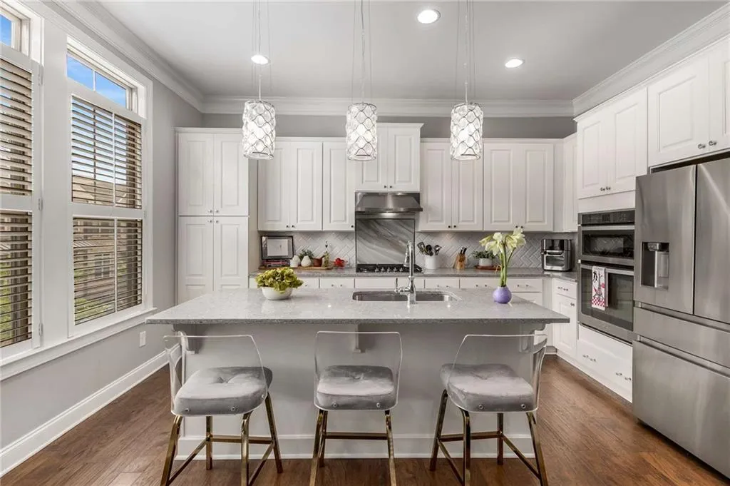 Kitchen featuring decorative backsplash, stainless steel appliances, under cabinet range hood, white cabinets, and a sink