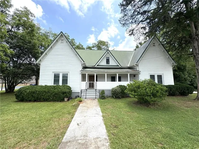 White siding exterior with a green metal roof and front porch