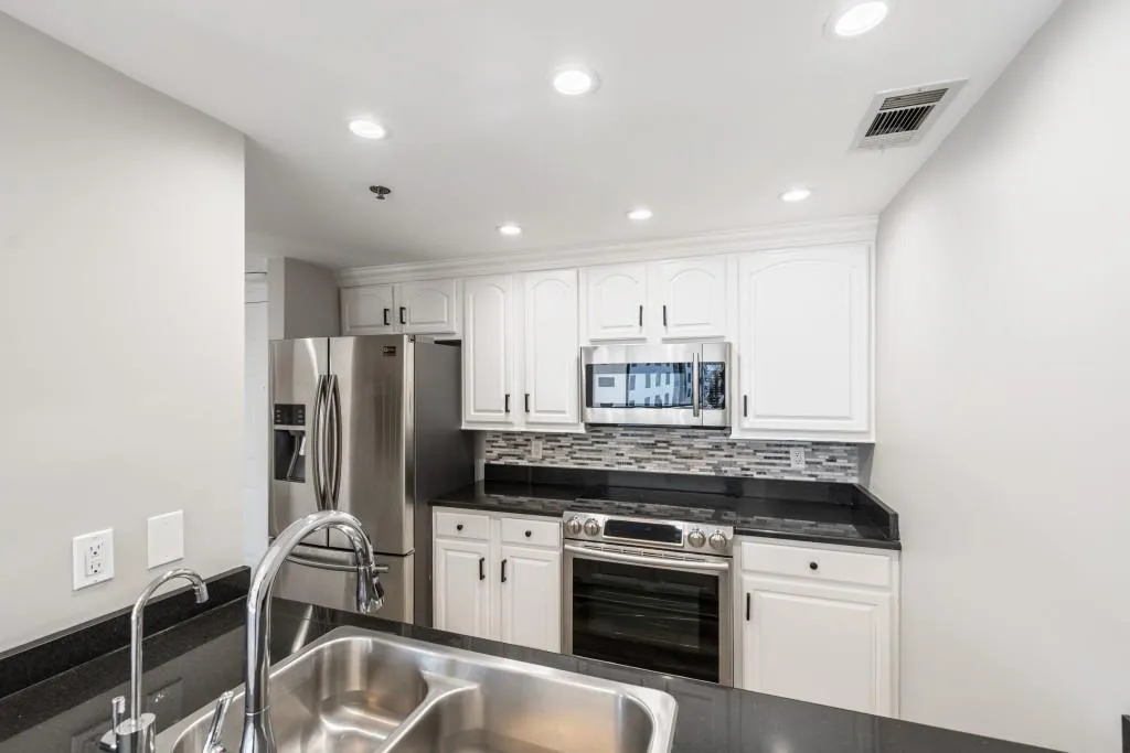 Renovated kitchen with granite counters, white cabinets, hands-free on/off faucet, hot water dispenser, & newer stainless steel appliances