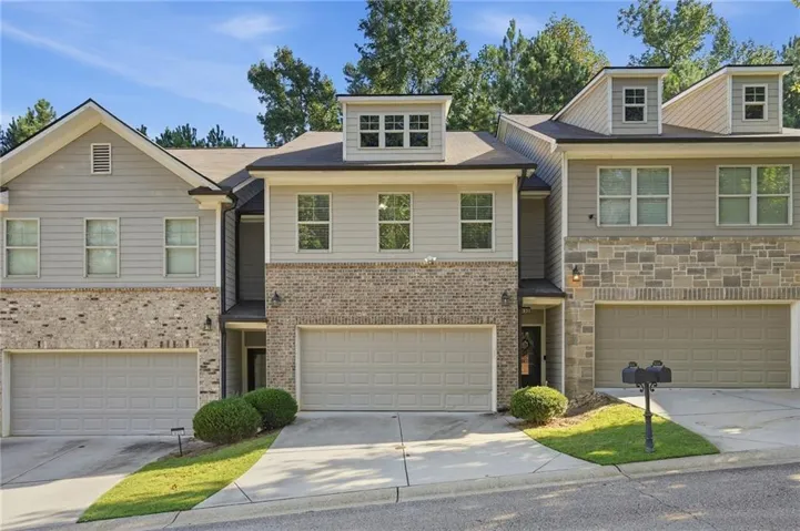 Two-story façade featuring brick and siding, multiple dormer windows, and a two-car garage