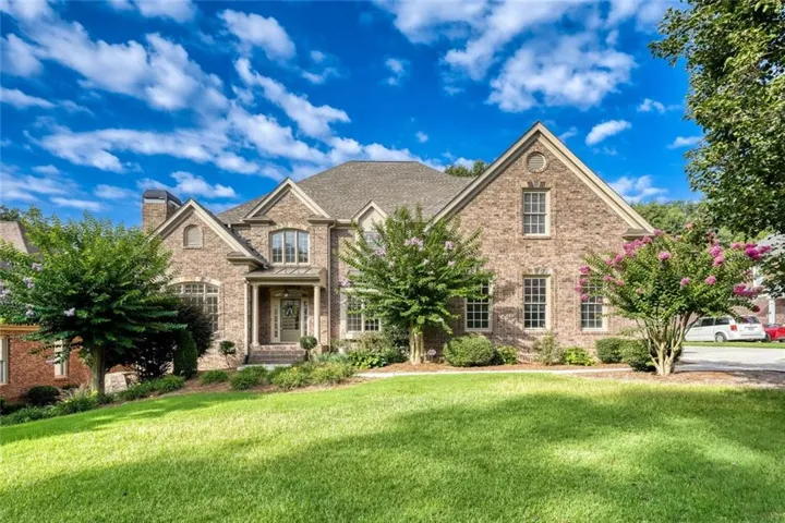 Traditional-style residence featuring a brick facade, gabled rooflines, and a covered entry porch