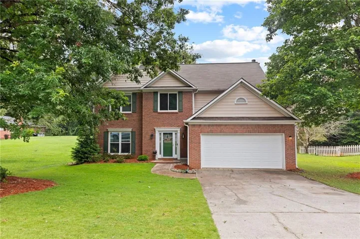 Traditional brick exterior featuring a multi-pane front door, shuttered windows, and an attached two-car garage