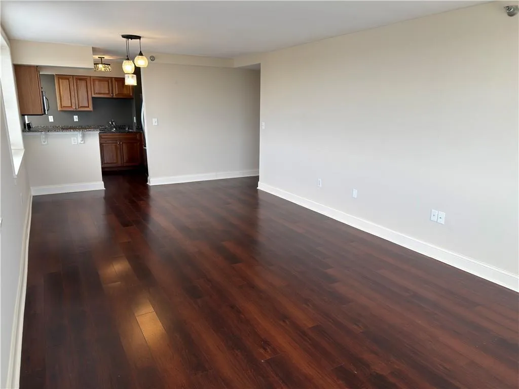 Kitchen with wood finish cabinetry, dark wood finished floors, decorative light fixtures, and open floor plan
