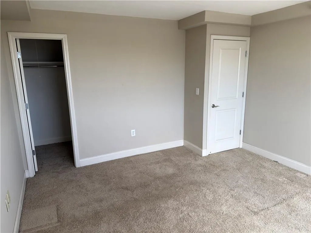 Unfurnished bedroom featuring carpet and a spacious closet