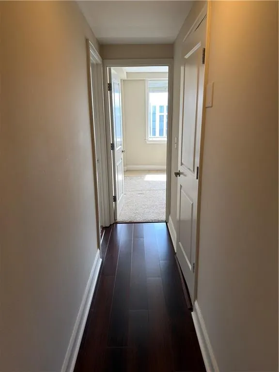 Hall featuring baseboards and dark wood finished floors