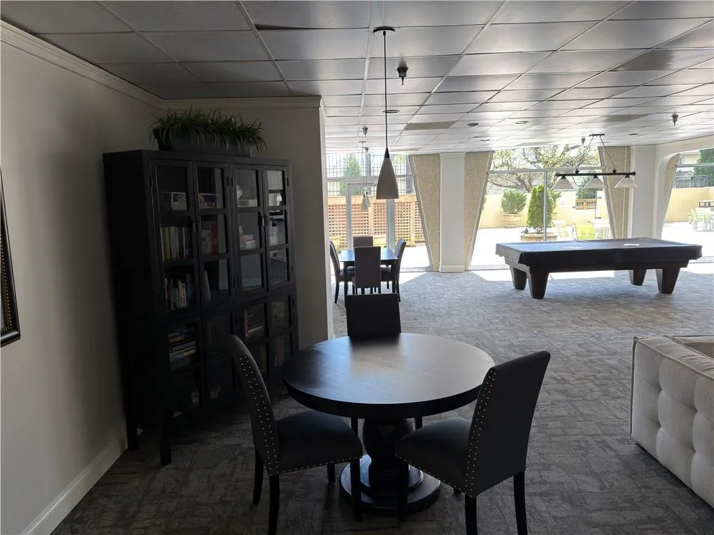 Dining room with pool table, carpet, a drop ceiling, and ornamental molding