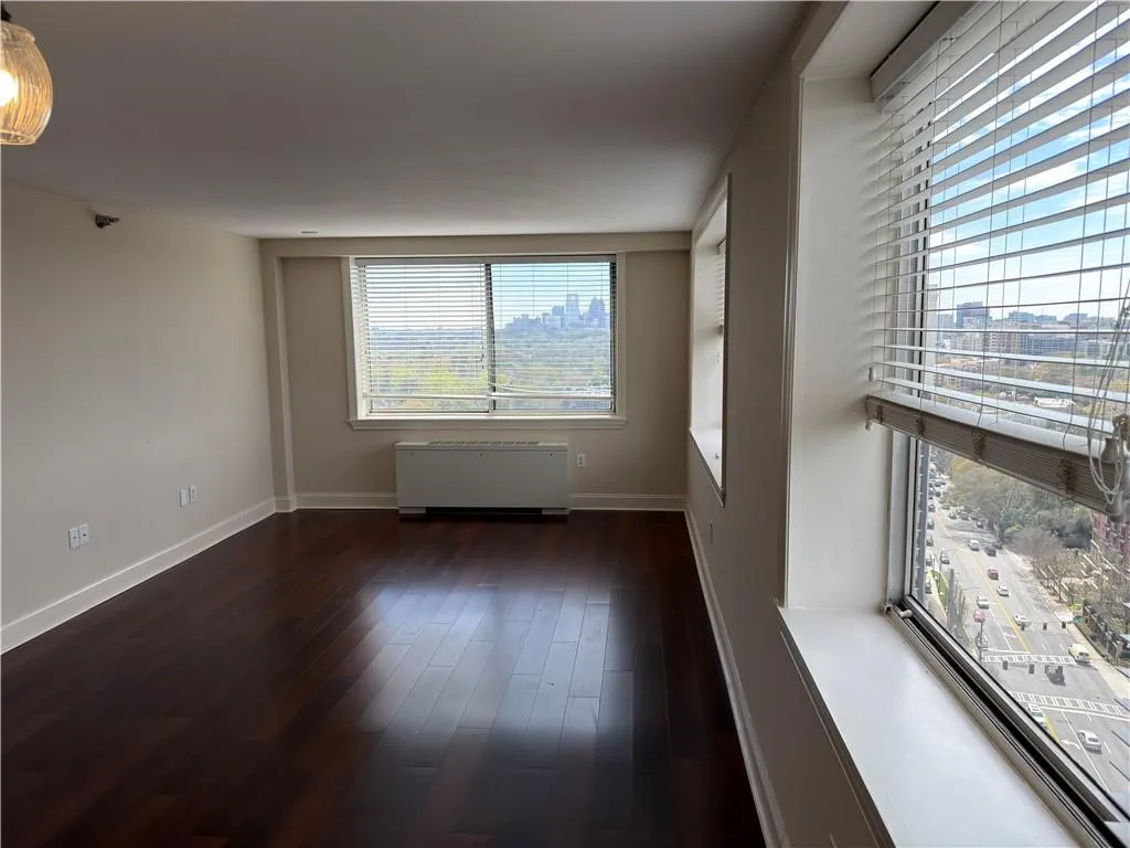 Spare room featuring dark wood-style flooring, radiator, and a city view