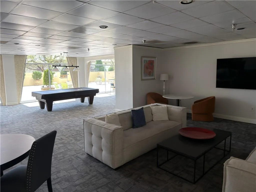 Carpeted living room with pool table, a paneled ceiling, and ornamental molding