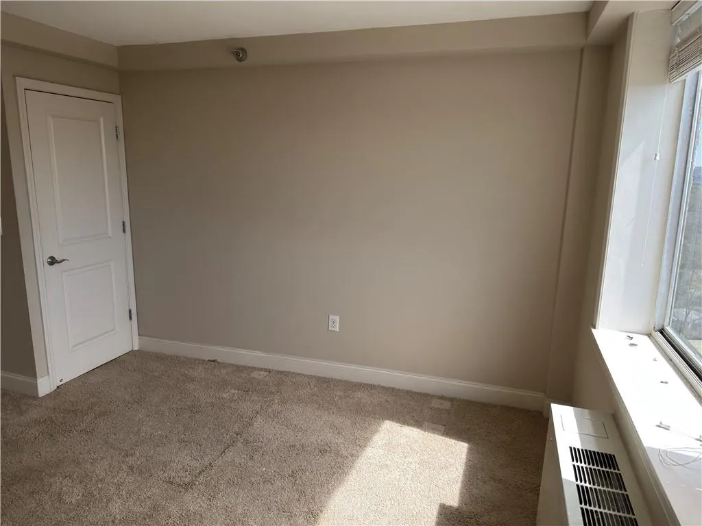 Empty room featuring light colored carpet and baseboards