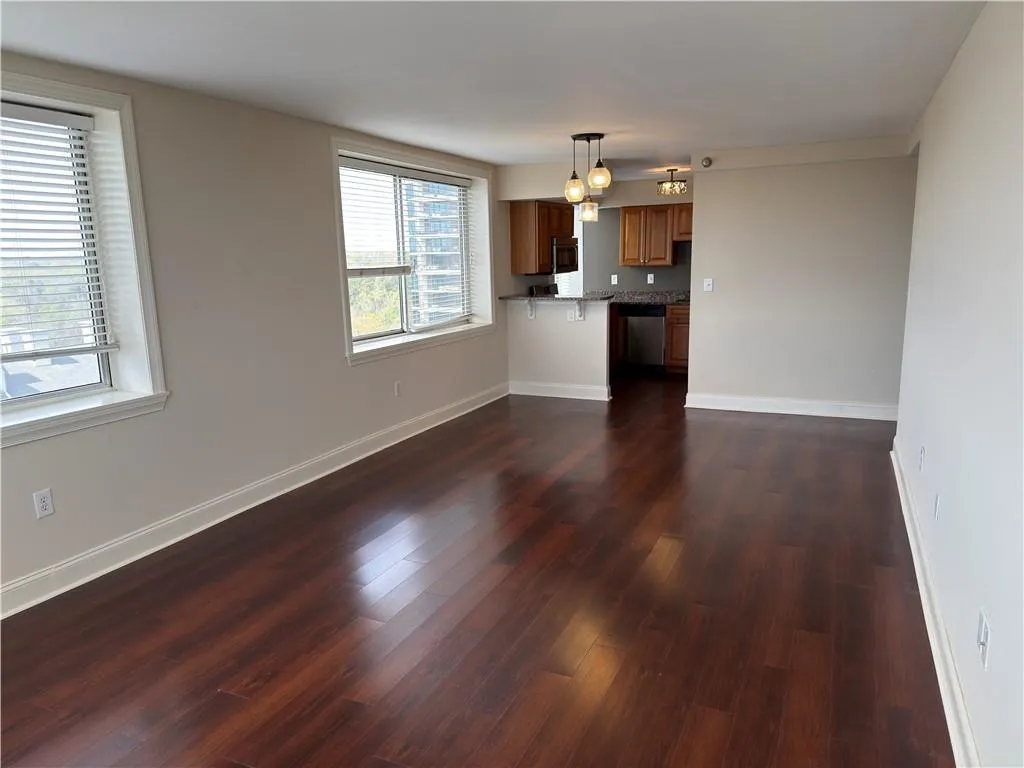 Unfurnished living room with baseboards and dark wood-style flooring