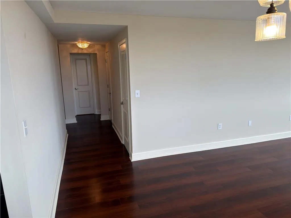 Corridor featuring dark wood-type flooring and baseboards