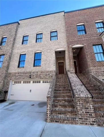 Brick exterior with arched windows, a single car garage, and a concrete driveway