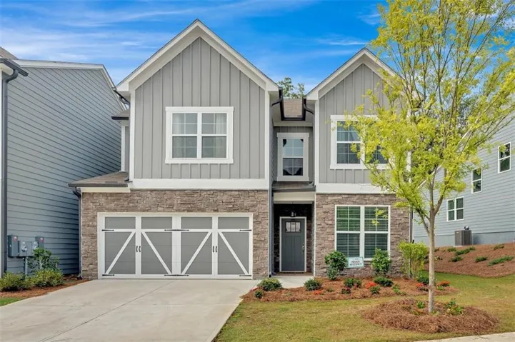 Contemporary two-story exterior featuring a stacked stone facade and board and batten siding