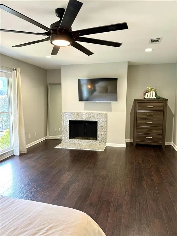 Unfurnished living room featuring ceiling fan and dark wood-type flooring