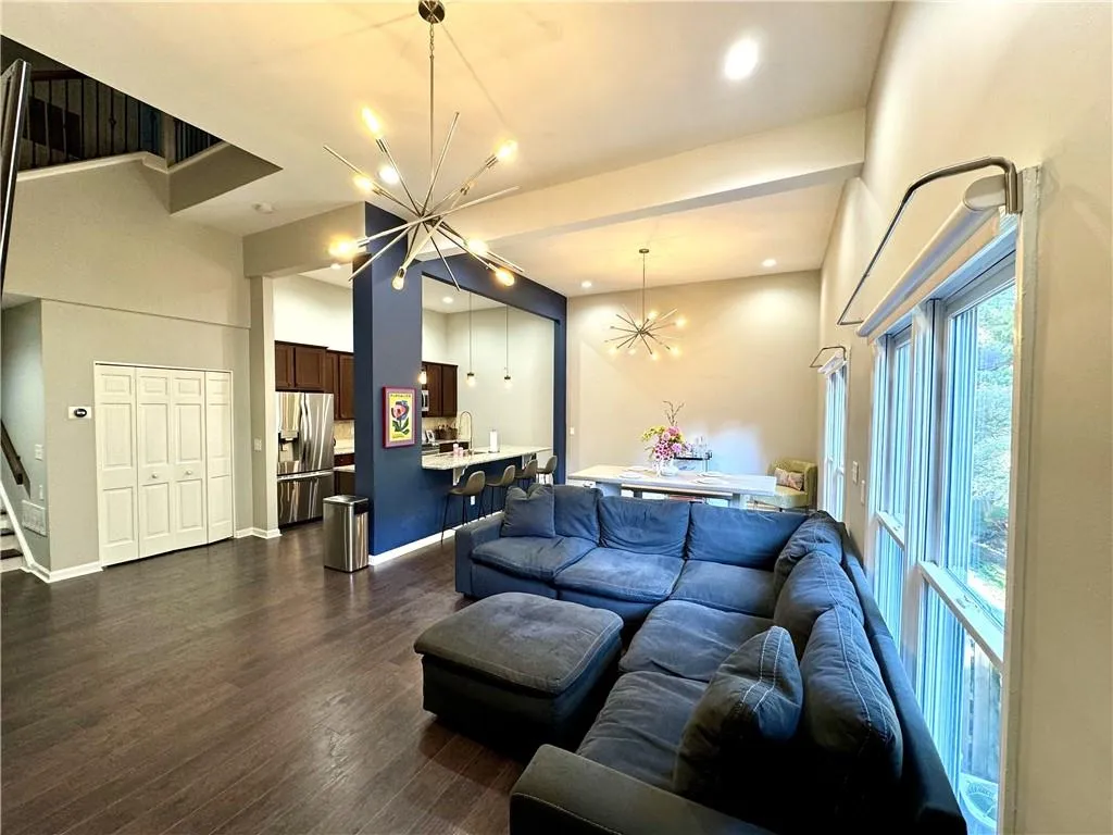 Living room with sink, an inviting chandelier, dark hardwood / wood-style floors, and a high ceiling
