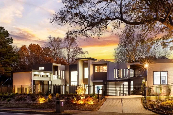 Contemporary house featuring a balcony, a fenced front yard, and stucco siding