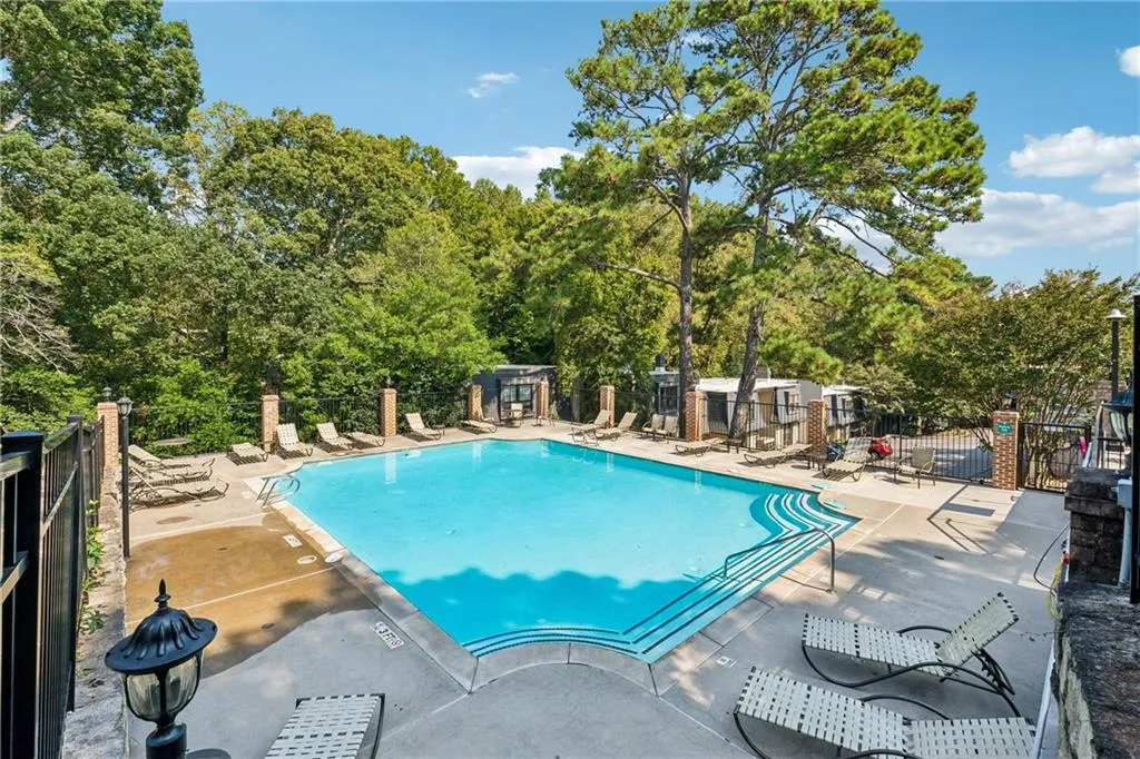 Community pool with a patio and view of wooded area