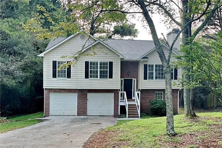 Split-level residence featuring a brick and siding exterior, two-car garage, and a prominent front entry with a white railing