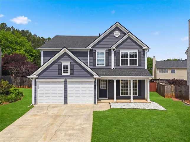 Two-story residence featuring blue siding, a two-car garage, and a covered front porch with white columns