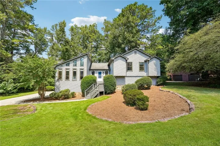 Exterior siding, multi-level design, front entry deck, landscaping, and a paved driveway