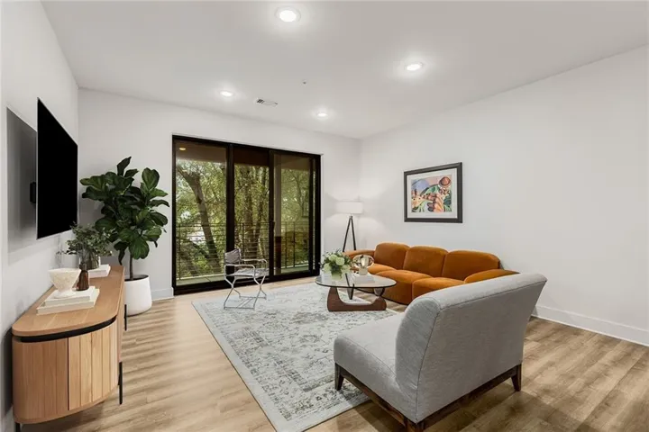 Recessed lighting, wood-finish flooring, sliding glass doors, white walls, and a private balcony