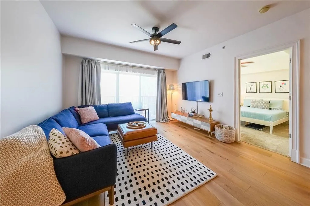 Living area with wood finished floors, a ceiling fan, and visible vents