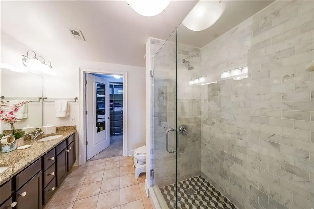 Full bathroom with tile patterned flooring, double vanity, visible vents, a sink, and a stall shower