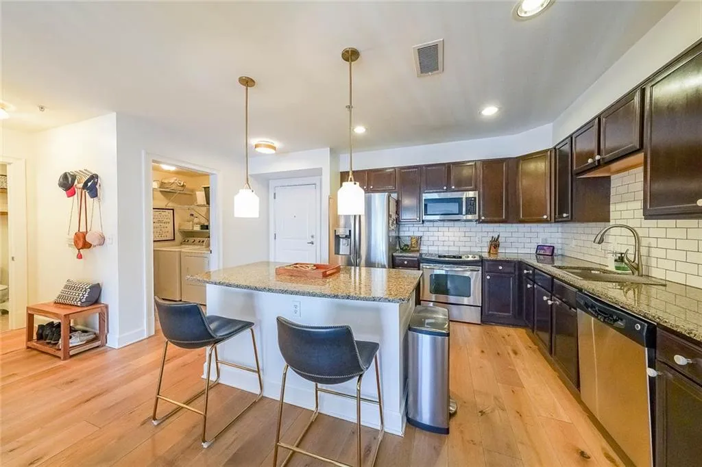 Kitchen featuring a sink, washing machine and dryer, visible vents, a breakfast bar, and appliances with stainless steel finishes