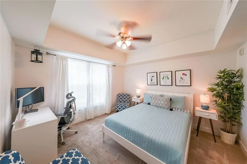 Bedroom featuring a raised ceiling, ceiling fan, baseboards, and carpet