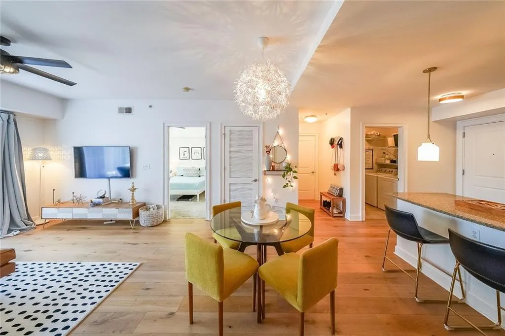 Dining space featuring washing machine and dryer, visible vents, light wood finished floors, and ceiling fan with notable chandelier