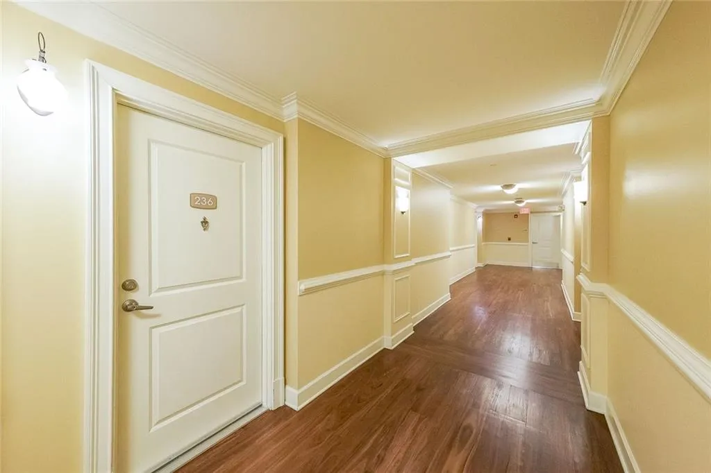 Corridor with ornamental molding and dark wood-style flooring