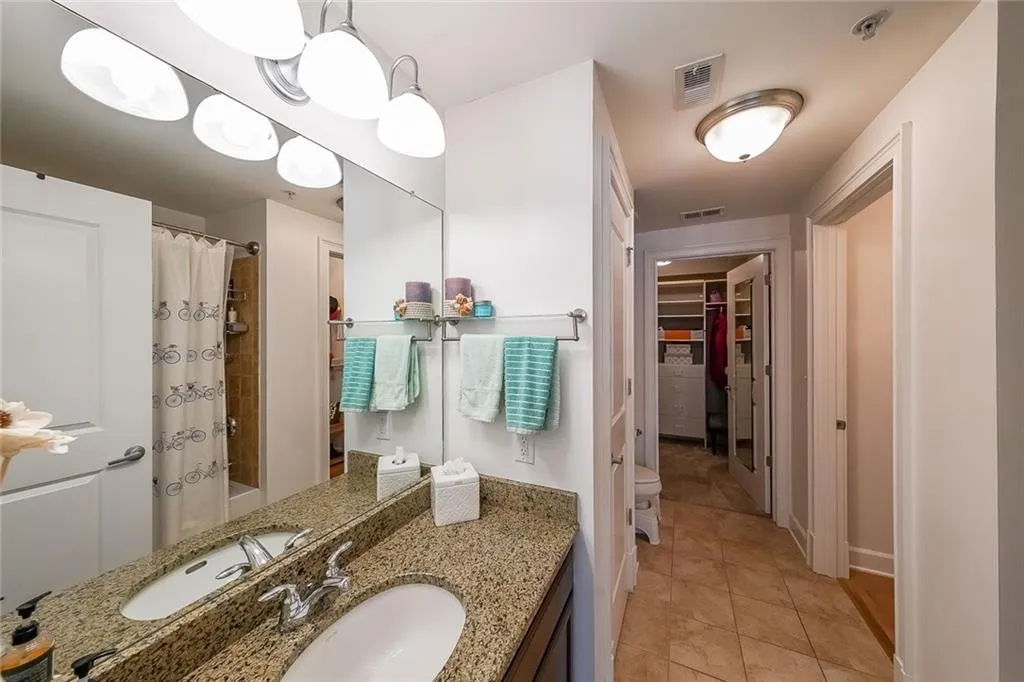 Full bathroom with tile patterned floors, visible vents, vanity, a walk in closet, and a shower with shower curtain