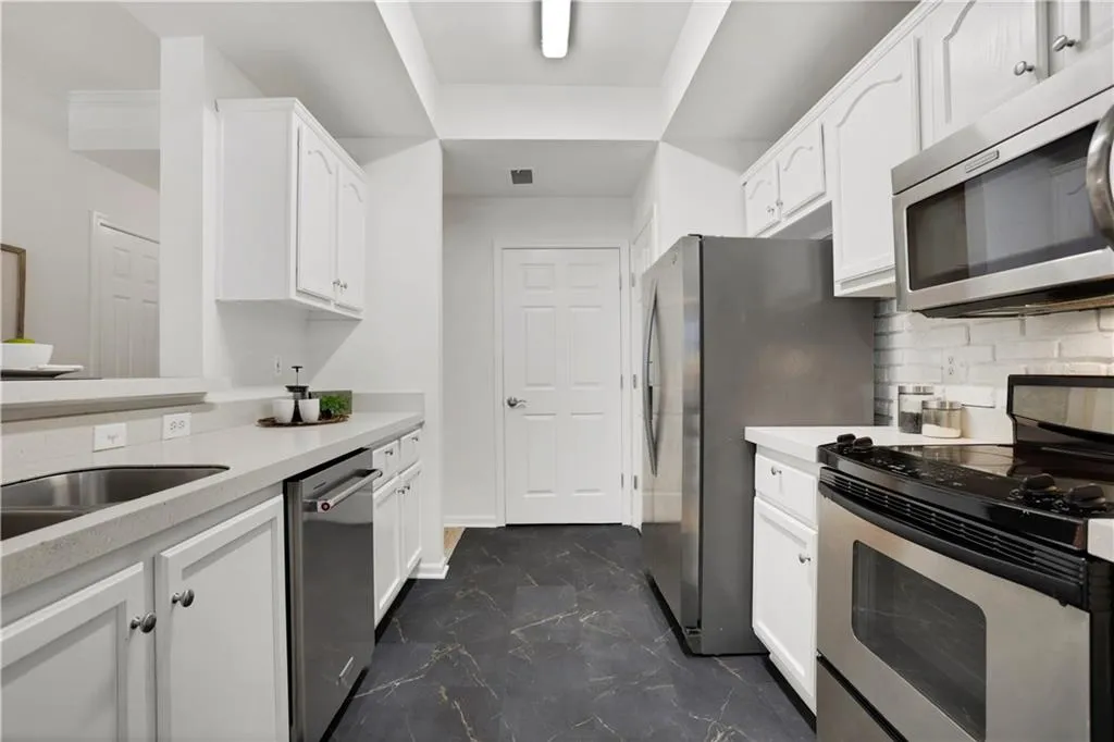 Kitchen featuring stainless steel appliances, white cabinets, and decorative backsplash