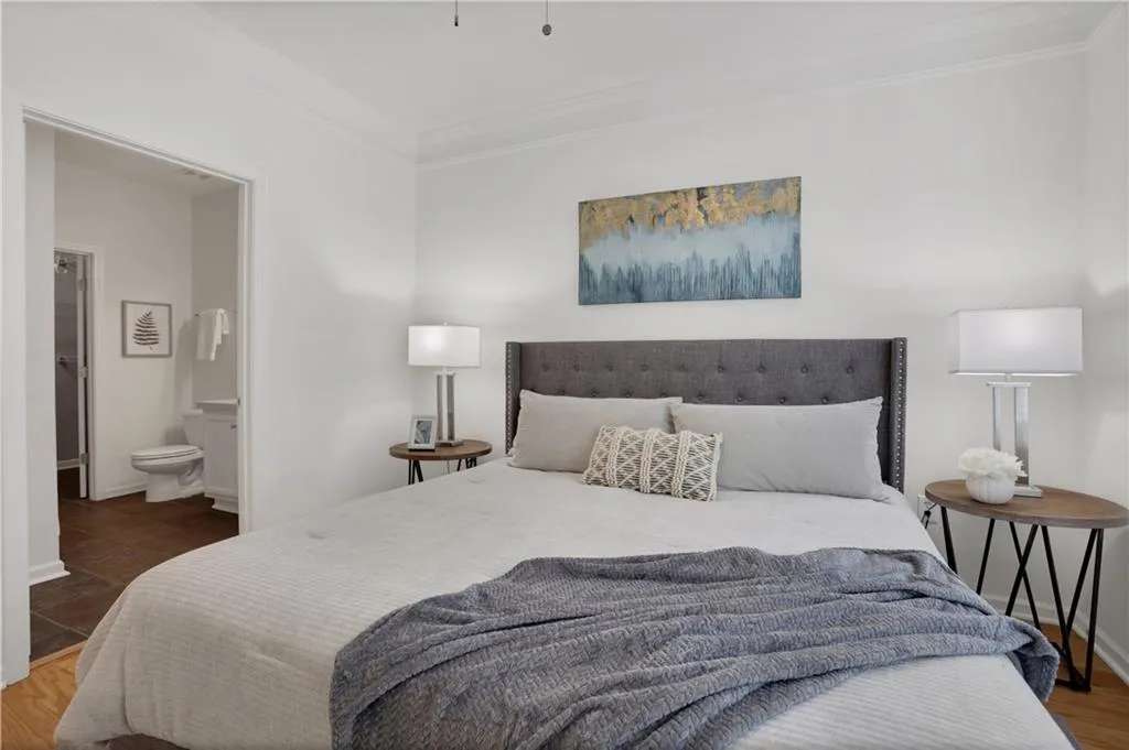 Bedroom featuring crown molding, wood finished floors, and ensuite bath