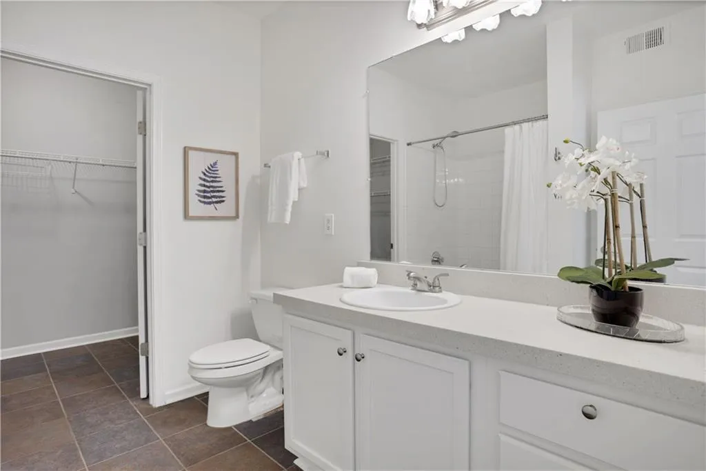 Bathroom featuring a spacious closet, vanity, and tiled shower
