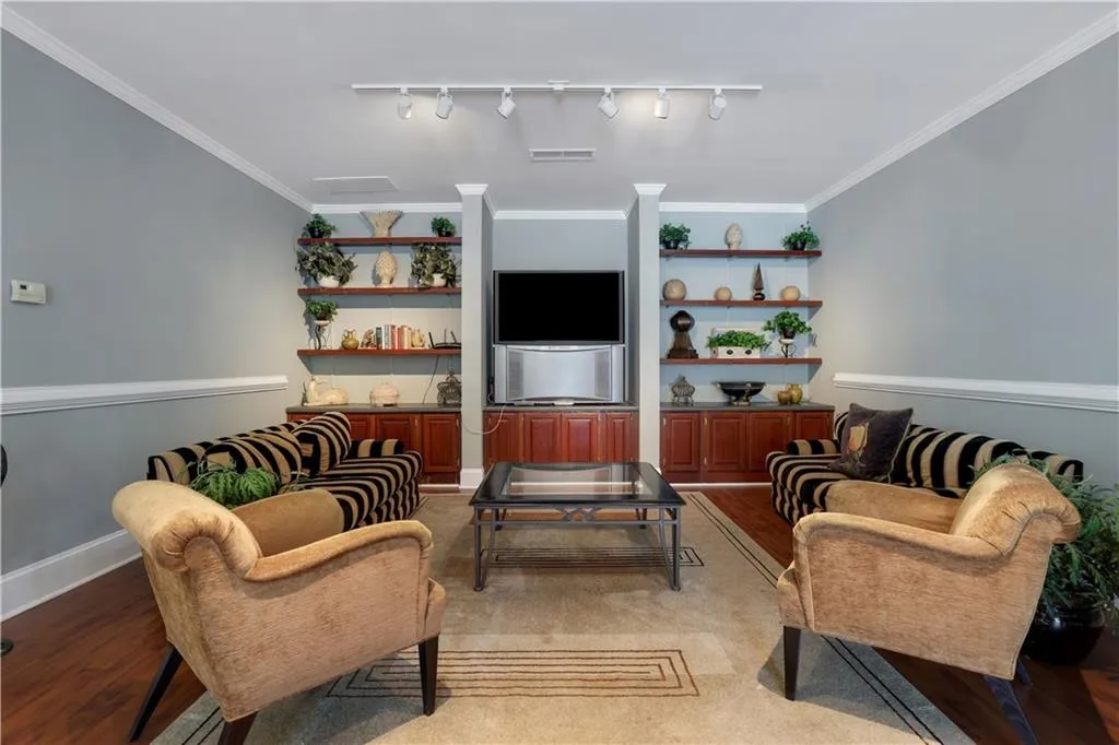 Living room featuring track lighting, built in features, light wood-type flooring, and ornamental molding