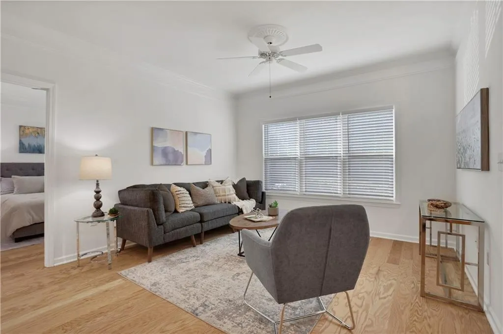 Living room with light wood-type flooring, a ceiling fan, and ornamental molding
