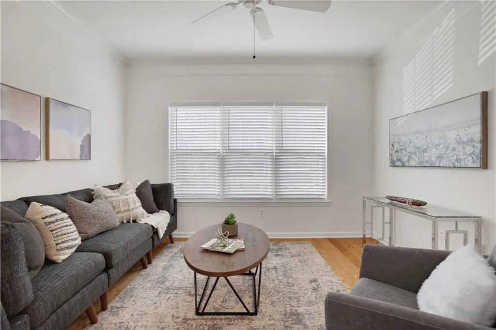 Living room featuring ceiling fan, ornamental molding, and light wood-type flooring