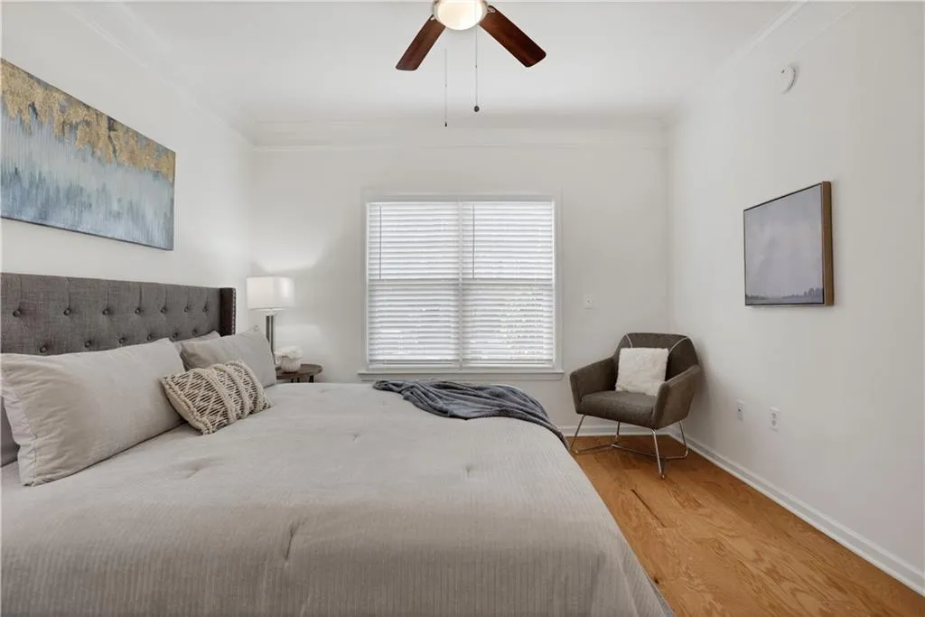 Bedroom featuring light wood-style floors, crown molding, and ceiling fan