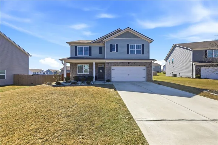 View of front of home featuring a garage, concrete driveway, brick siding, and covered porch